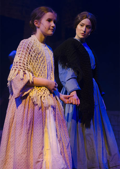 Jane Eyre in her period Victorian costume a blue dress with a stole  